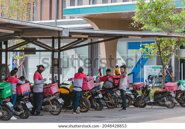 KANCHANABURI, THAILAND-AUGUST 22,2021 : Group\
of Food Panda delivery service riders wear face mask parking\
motorbike to relax and wait to get food from restaurant at parking\
lot in front of\
Robinson.