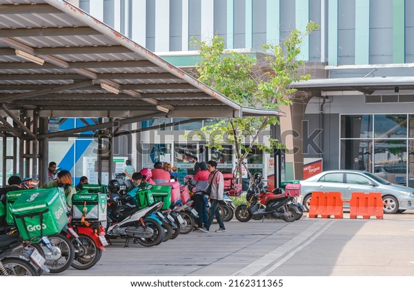 KANCHANABURI, THAILAND-AUGUST 22,2021 : Group of\
Food delivery service riders park motorbike to relax and wait to\
get food from the restaurant at parking lot in front of Robinson\
Department Store.