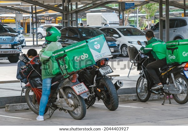KANCHANABURI,\
THAILAND-AUGUST 22,2021 : Group of Grab riders park motorbike to\
relax and wait to get food from the restaurant at parking lot in\
front of Robinson Department\
Store.