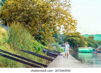 KANCHANABURI, THAILAND-SEPTEMBER 5,2020 : Unidentified Asian Grandfather And Grandchild Wear Protective Face Mask To Prevent Coronavirus (COVID-19) Walking On Wooden Bridge Along River At Din Cafe.