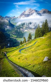 Kandersteg, Switzerland - 21 August 2019. A Tourist On A Tobggan Sledge On A Toboggan Slide Rail Near Oeschinensee Lake In Kandersteg, Switzerland