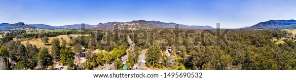 Kangaroo valley around Kangaroo river
crossed by historic Hampden bridge surrounded by mountain ranges
protecting agricultural farms and green
pastures.
