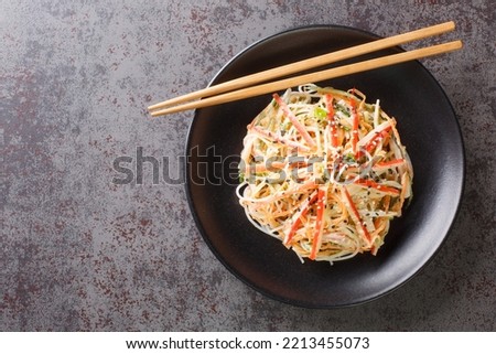 Kani or kanikama salad is a Japanese crab salad that is a delicious mix of crab meat crunchy cucumber and carrots and spicy mayonnaise dressing closeup in the plate on the table. Horizontal top view
