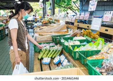 Kaohsiung, Taiwan - May 12, 2021: Female customers pick out vegetables at a large traditional market in North Kaohsiung, Taiwan.