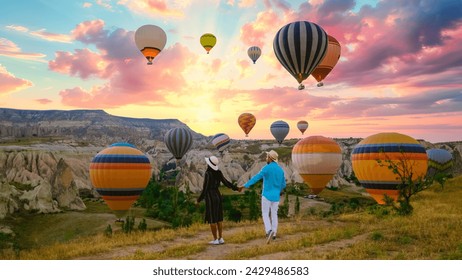 Kapadokya Cappadocia Turkey, a happy young couple during sunrise watching the hot air balloons of Kapadokya Cappadocia Turkey during vacation, a diverse couple of an Asian woman and caucasian man - Powered by Shutterstock