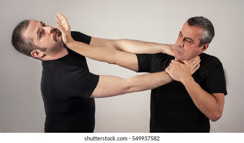 Kapap instructor demonstrates street fighting self defense technique against holds and grabs with his student - Powered by Shutterstock