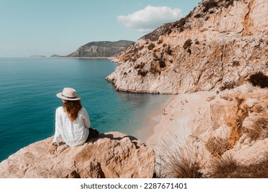 Kaputas Beach Turkey - woman on the rock watching a beautiful sea view and a sandy beach below in summer time. - Powered by Shutterstock