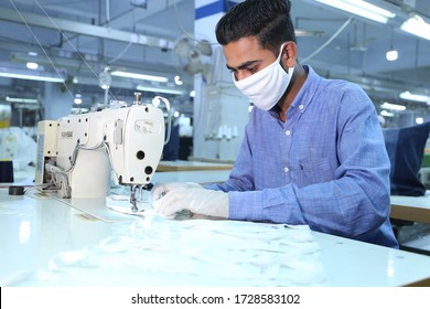 Karachi, Pakistan - May 02, 2020:  Young tailor seamstress working in textile factory stitching cloths surgical mask . male Worker Wearing Protective mask in textile factory
