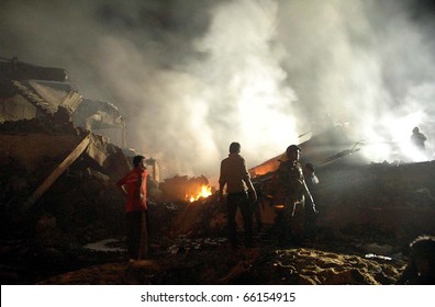 KARACHI, PAKISTAN - NOV 28: People Gather In Front Of Burning Wreckage Of Plane At The Site Of Plane Crash Incident On Early Morning On November 28, 2010 In Karachi.