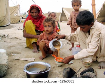 KARACHI, PAKISTAN, OCT 03: Flood affectee child serves tea to his family members at their make-shift tent house at relief camp established at Hawks Bay area on October 3, 2010 in Karachi, Pakistan.