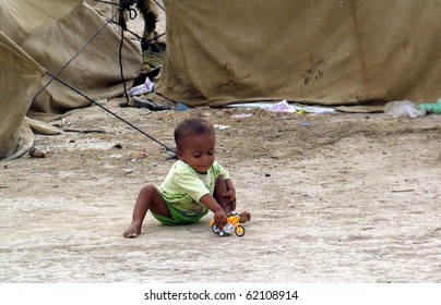 KARACHI, PAKISTAN, SEPT 30: Flood affected child plays with his toy at his make shift tent  house at flood affectees relief camp established at Hawks bay area on September 30, 2010 in KARACHI, PAKISTAN