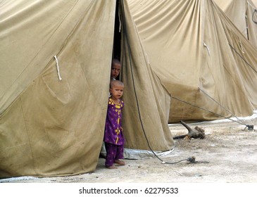 KARACHI, PAKISTAN, SEPT 30: Flood affected children look out from their make shift tent  house at flood affectees relief camp established at Hawks bay area on September 30, 2010 in Karachi, Pakistan.