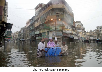 KARACHI, PAKISTAN - SEPTEMBER 13: A rain affected family travels at a flooded area due to heavy downpour of Monsoon Season in Karachi on Tuesday, September 13, 2011.