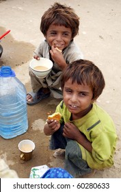 KARACHI, PAKISTAN-AUG 31: Flood affected children eat snack with tea at flood relief camp established at Razzaqabad area in Karachi on Tuesday, August 31, 2010. (Rizwan Ali/PPI Images).