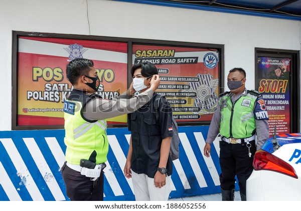 KARANGANYAR, INDONESIA - NOVEMBER 10 2020: The\
Indonesian traffic police carry out disciplinary operations on the\
COVID-19 prevention health protocol. Distributing and helping to\
wear masks to\
people.