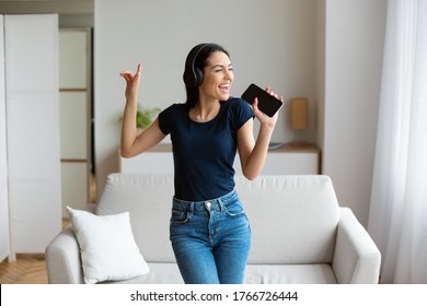 Karaoke App. Woman In Headphones Singing Listening To Music Holding Phone Like Microphone At Home