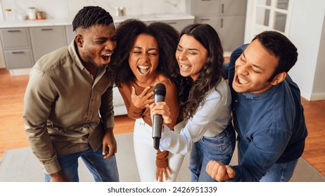 Karaoke party. Diverse friends gathering in home living room, celebrating with joyful singing and relaxation, creating lively atmosphere of friendship and youthful joy on weekend. Panorama - Powered by Shutterstock