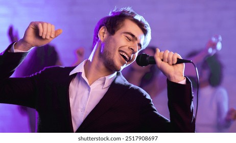 Karaoke Party. Young Man Singing Song Holding Microphone Having Fun Partying At Night Club With Friends. Panorama, Blue Light - Powered by Shutterstock