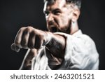 Karate fighter practicing punch in gym. Selective focus on fist. Strength and motivation. Screaming man in kimono ready for karate training. Angry karate man in fighting position. Mixed martial art.