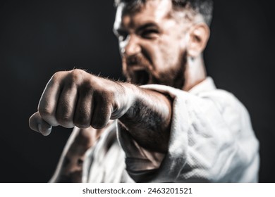 Karate fighter practicing punch in gym. Selective focus on fist. Strength and motivation. Screaming man in kimono ready for karate training. Angry karate man in fighting position. Mixed martial art. - Powered by Shutterstock