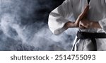 Karate fighter in smoke on black background, closeup. Banner design with space for text