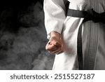 Karate fighter in smoke on black background, closeup