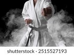 Karate fighter in smoke on black background, closeup