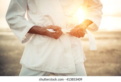 Karate fighter tying his kimono belt up, concept about martial arts - Powered by Shutterstock