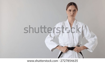 Karate fighter in uniform on light grey background, space for text