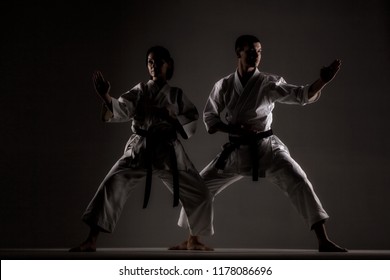 karate girl and boy posing against dark background
