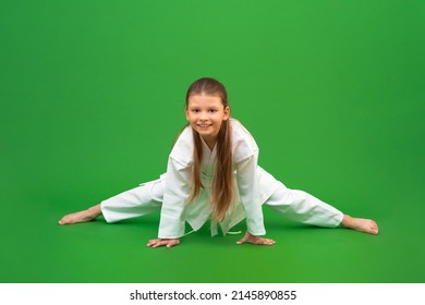 A karate girl does stretching before training in the gym. The child is engaged in martial arts.