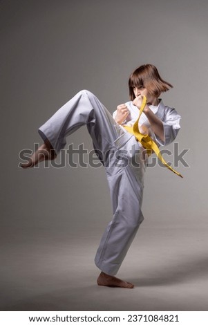 A karate girl trains in a kimono with punches and kicks