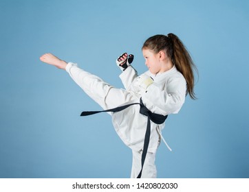 Karate gives feeling of confidence. Strong and confident kid. She is dangerous. Girl little child in white kimono with belt. Karate fighter ready to fight. Karate sport concept. Self defence skills.