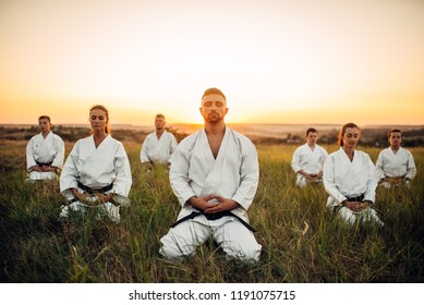 Karate group sitting on the ground and meditates - Powered by Shutterstock