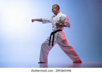 Karate, Judo, Taekwondo Martial Art Sportsman Training Over Gradient White Blue Background. Man Standing In Straight Punch Karate Pose. Concept Of Martial Art, Combat Sport, Energy, Fit, Ad