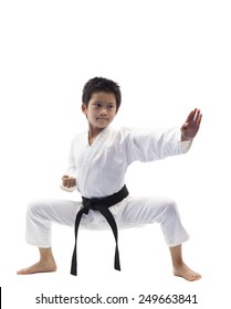 Karate kid wearing white gi and black belt performing knife hand block in horse stance.