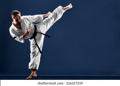 Каратэ человек в кимоно бьет ногу на синем фоне