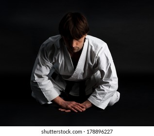 Karate Man In Kimono Making Traditional Bow On A Black Background