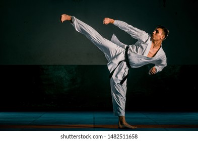 Karate man posing on a dark background wearing white kimono