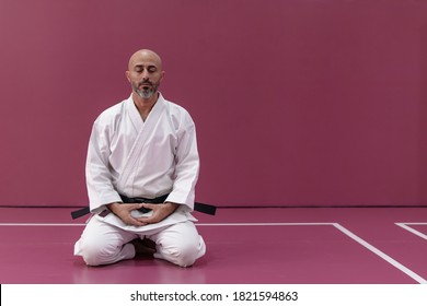 Karate master with black belt rank, in meditation position in his dojo or martial arts school - Powered by Shutterstock