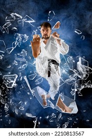 Karate Master Breaking With Leg Glass. Smoke Background 