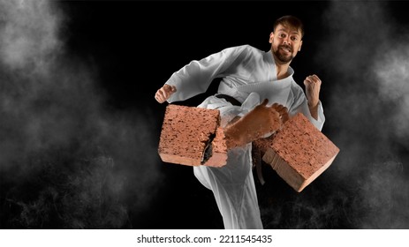 Karate Master Breaks A Brick With His Foot. Black Background