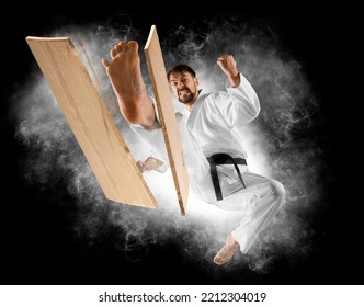 Karate Master Breaks A Wooden Board With His Foot. Smoke Background