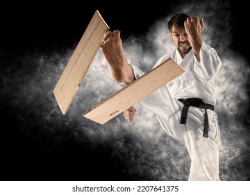 Karate masters breaking with leg wooden board. Smoke background  - Powered by Shutterstock