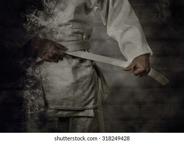 Karateka tying the white belt (obi) with grunge background