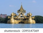 Karaweik Restaurant, a structure built to resemble a royal barge, floats on the serene waters of Kandawgyi Lake in Yangon, Myanmar, offering a unique dining experience