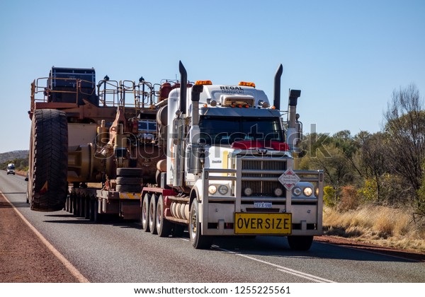 KARIJINI - WESTERN AUSTRALIA - JULY 11, 2018: The\
Western Star road train with Oversize sign and extremely wide\
dumper truck on an asphalt road in Western Australia near Karijini\
National Park.