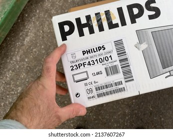 Karlsruhe, Germany - March 11, 2022: POV Male Hand Looking At Cardboard Package Caton Box Of Vintage Old Philips Widescreen Flat TV Moden 23PF4310 With Crystal Clear Technology And 23 Inch Size