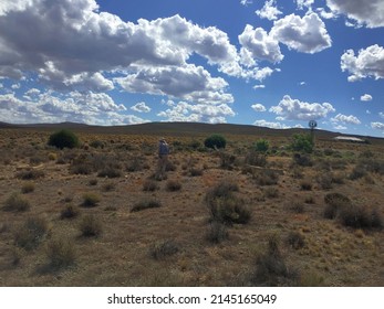 Karoo landscape near Sutherland, with luminous clouds and a windmill and house in the distance.