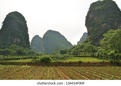 Karst Peaks In Yangshou China With Farmland In Foreground Under Gray Smoggy Sky